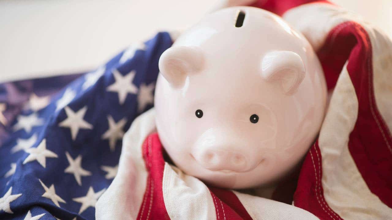 A smiling pink piggy bank resting atop a U.S. flag