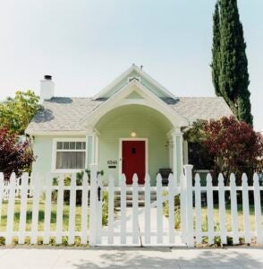 pale green house with white picket fence and red door