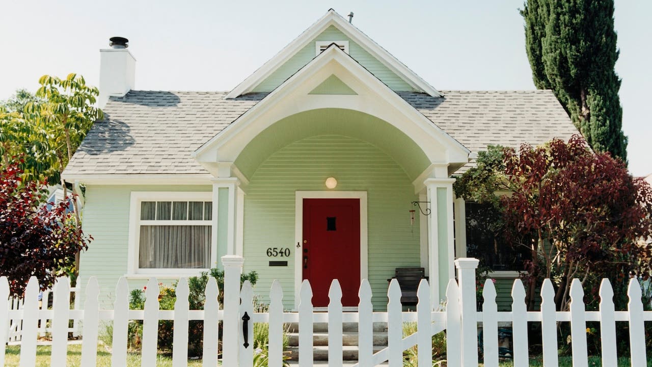 pale green house with white picket fence and red door