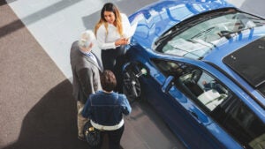 High angle view of saleswoman showing car to customers at showroom