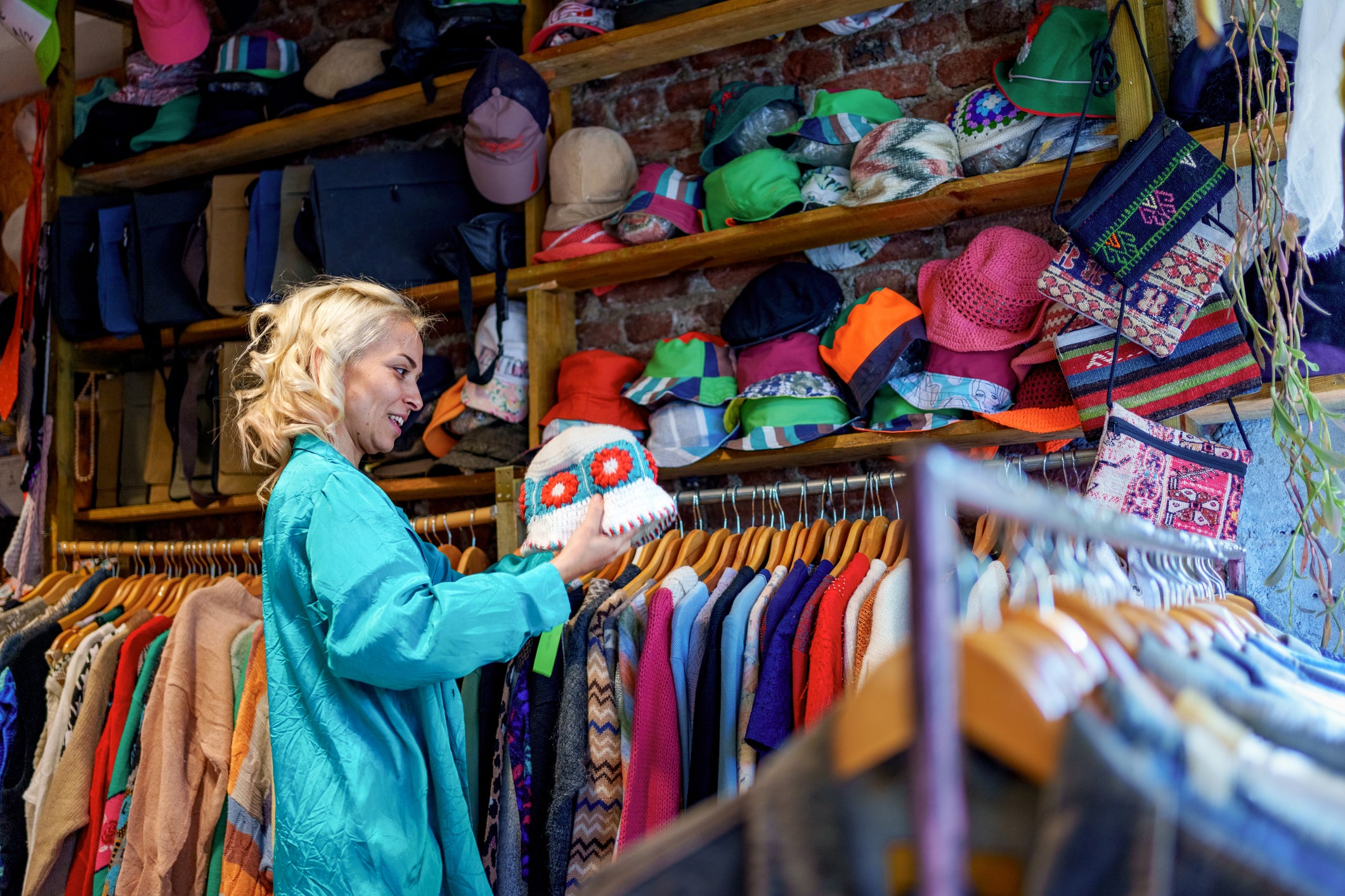 A woman browses through clothing racks filled with second-hand and vintage garments in a store.