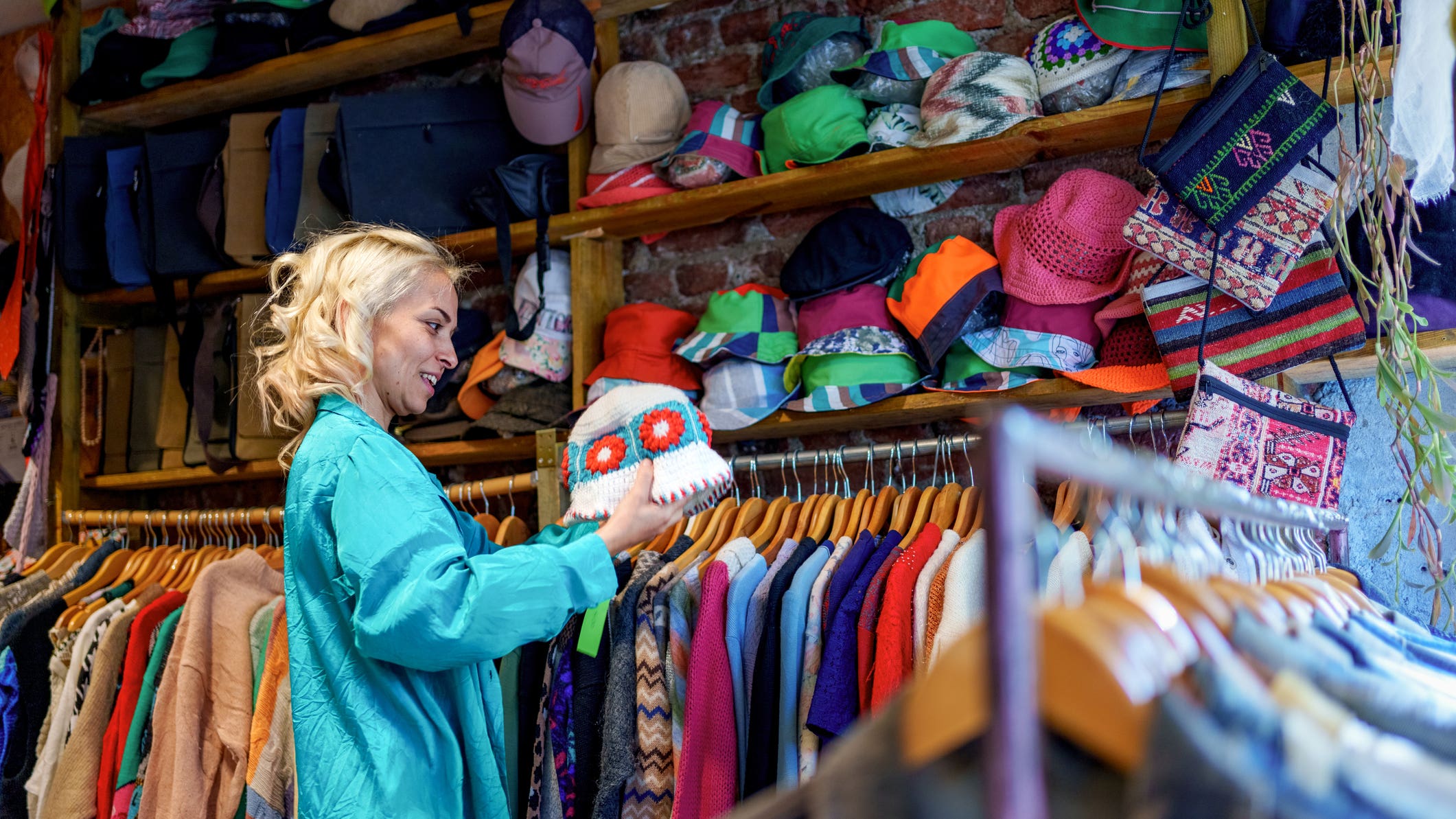 A woman browses through clothing racks filled with second-hand and vintage garments in a store.