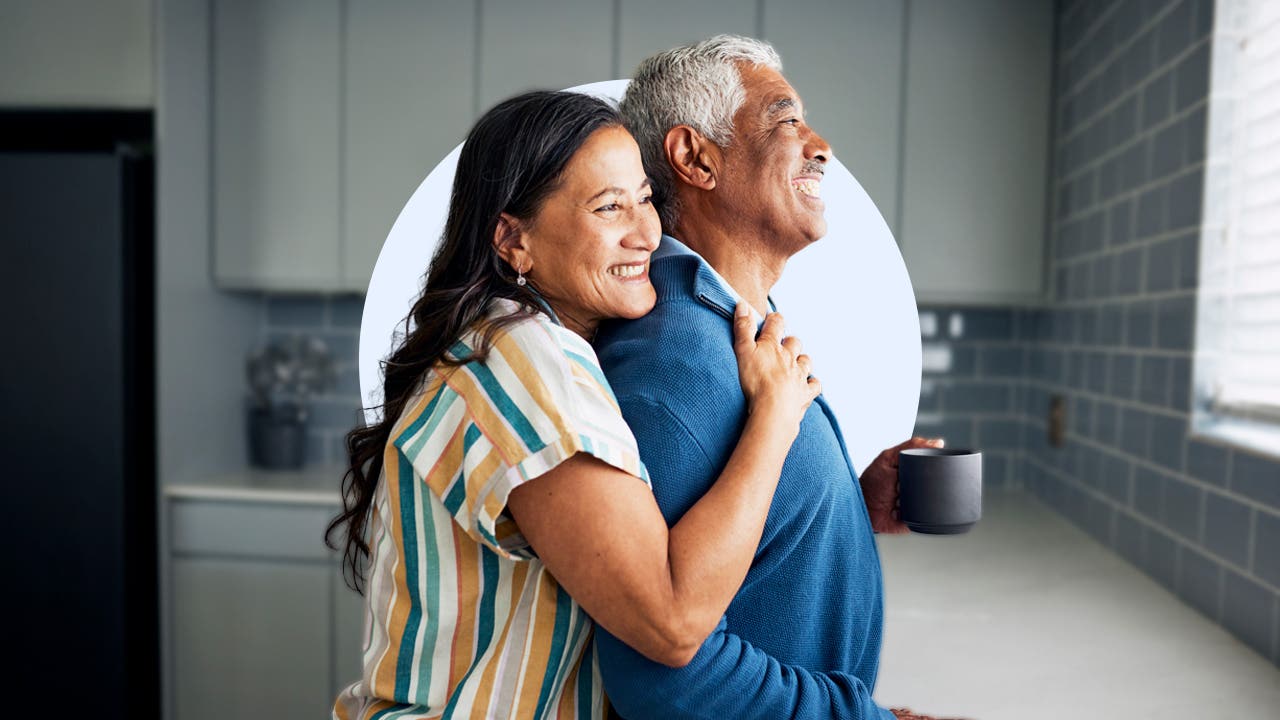 A couple embrace and smile in their kitchen.