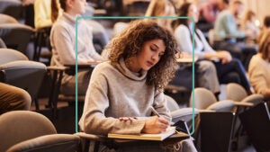 A woman takes notes in college.