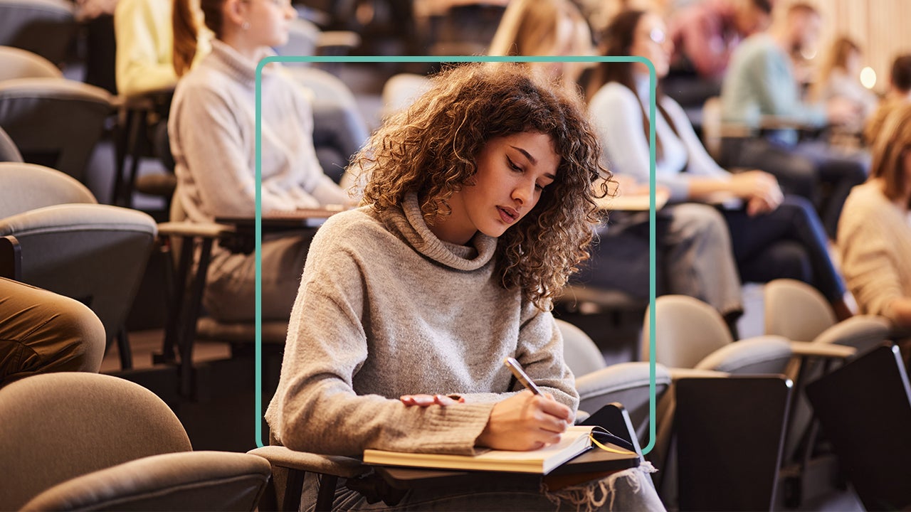 A woman takes notes in college.