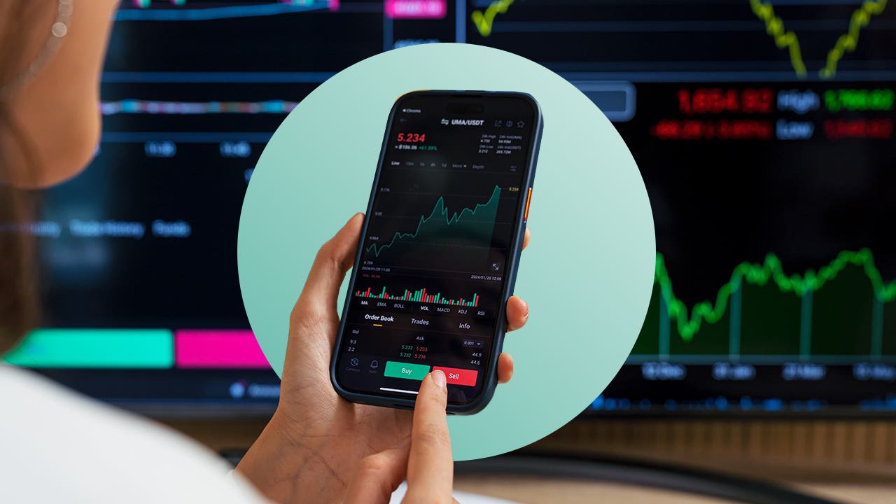 Image of a person holding a mobile phone that showing a stock performance graph with Buy and Sell buttons at the bottom of the screen.