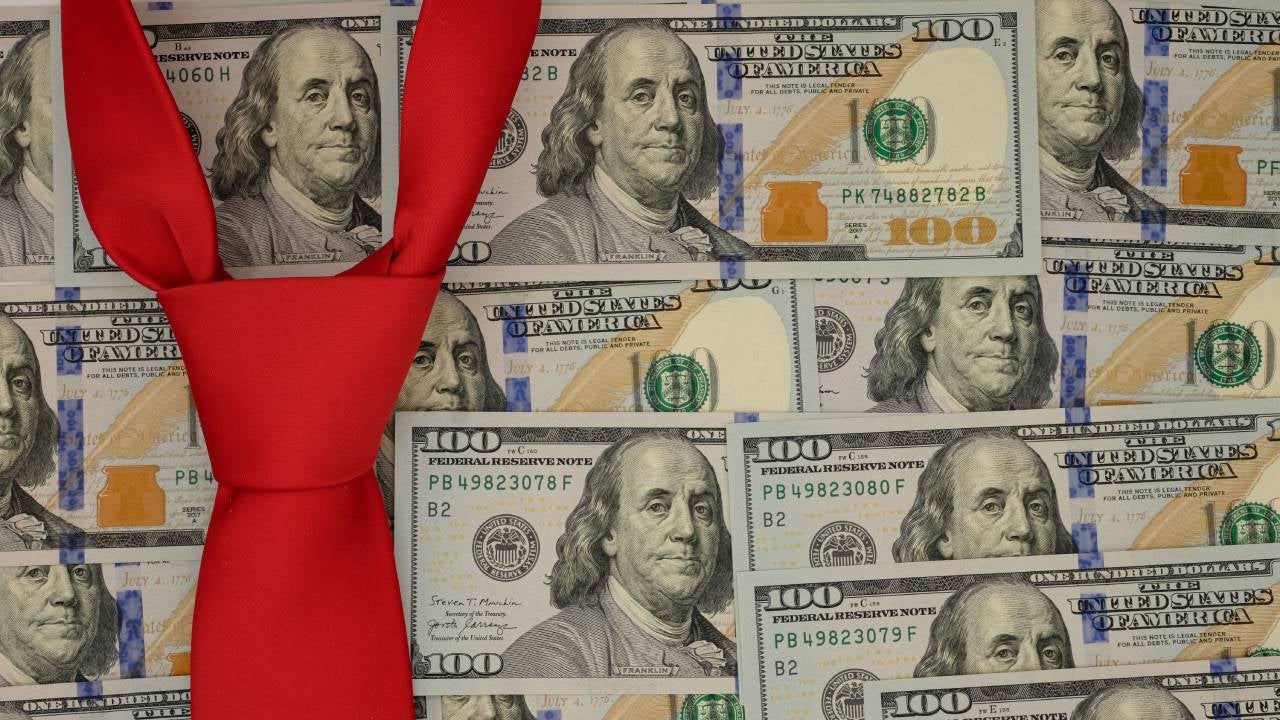 Conceptual image of several $100 bills arranged as wallpaper with a red necktie suggesting Donald Trump.