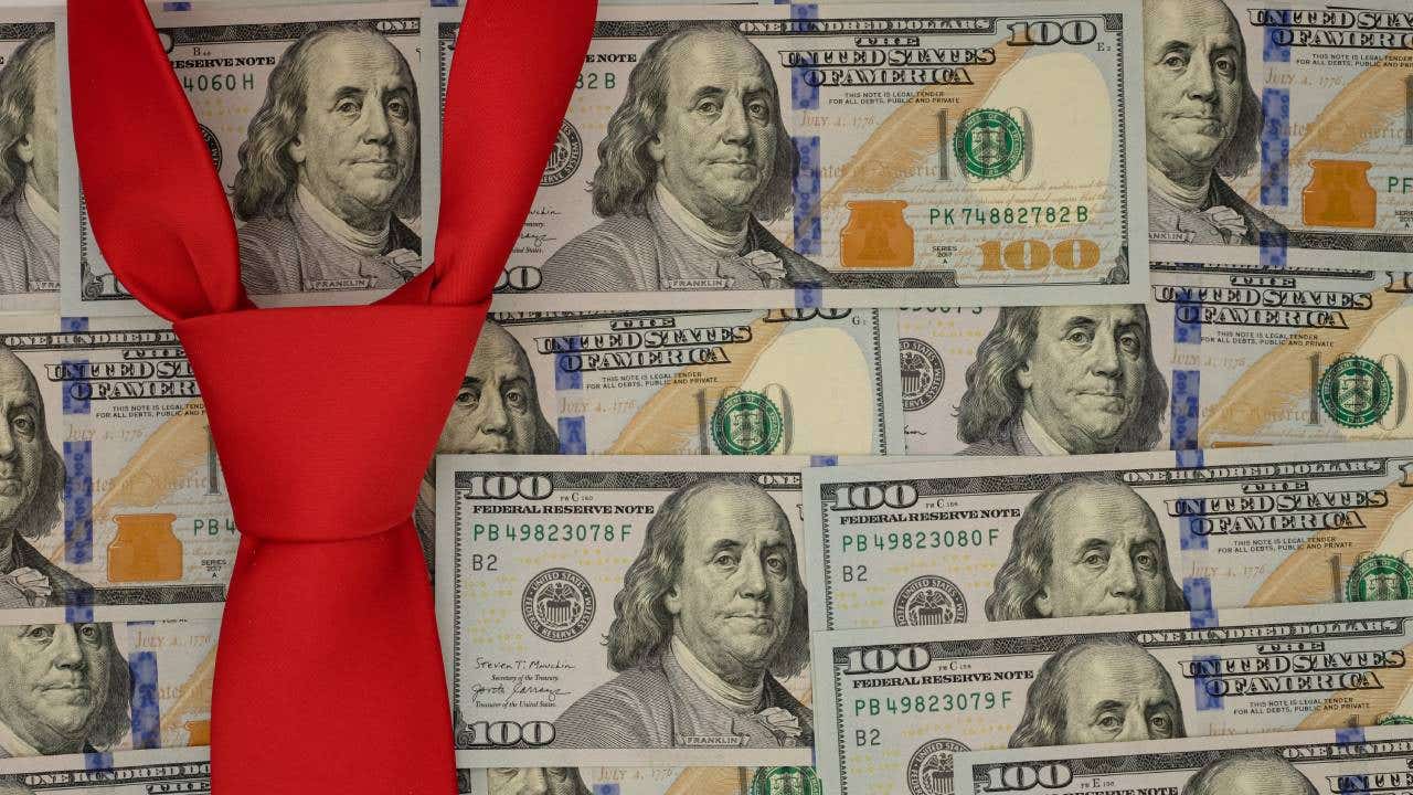 Conceptual image of several $100 bills arranged as wallpaper with a red necktie suggesting Donald Trump.