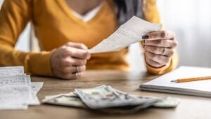Close-up of hands checking shopping receipts with money on table