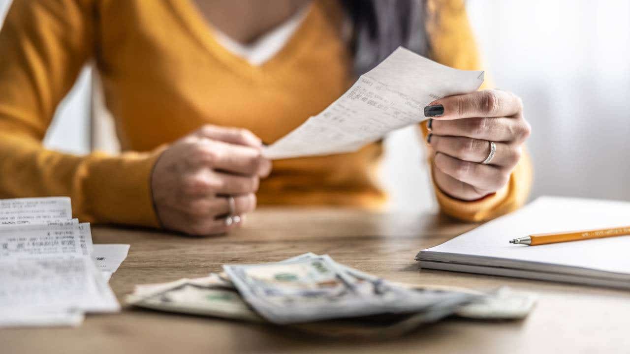 Close-up of hands checking shopping receipts with money on table