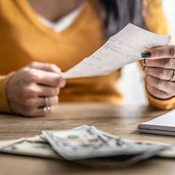 Close-up of hands checking shopping receipts with money on table