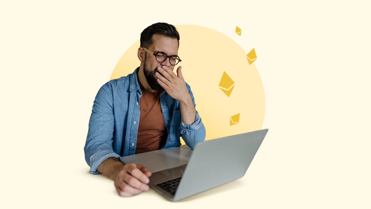 A man looks at his computer screen and yawns