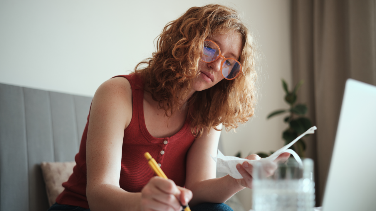 Young woman calculating her finances while sitting with her laptop.