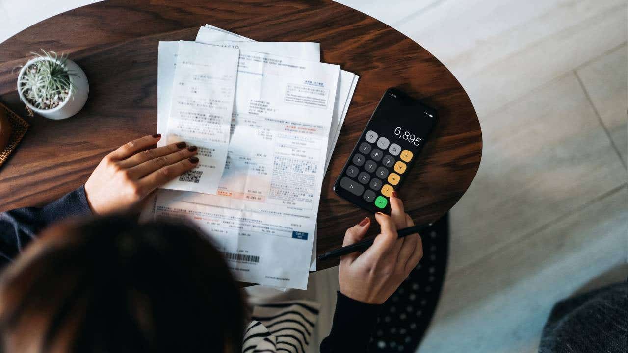Overhead view of young Asian woman managing personal banking and finance at home.
