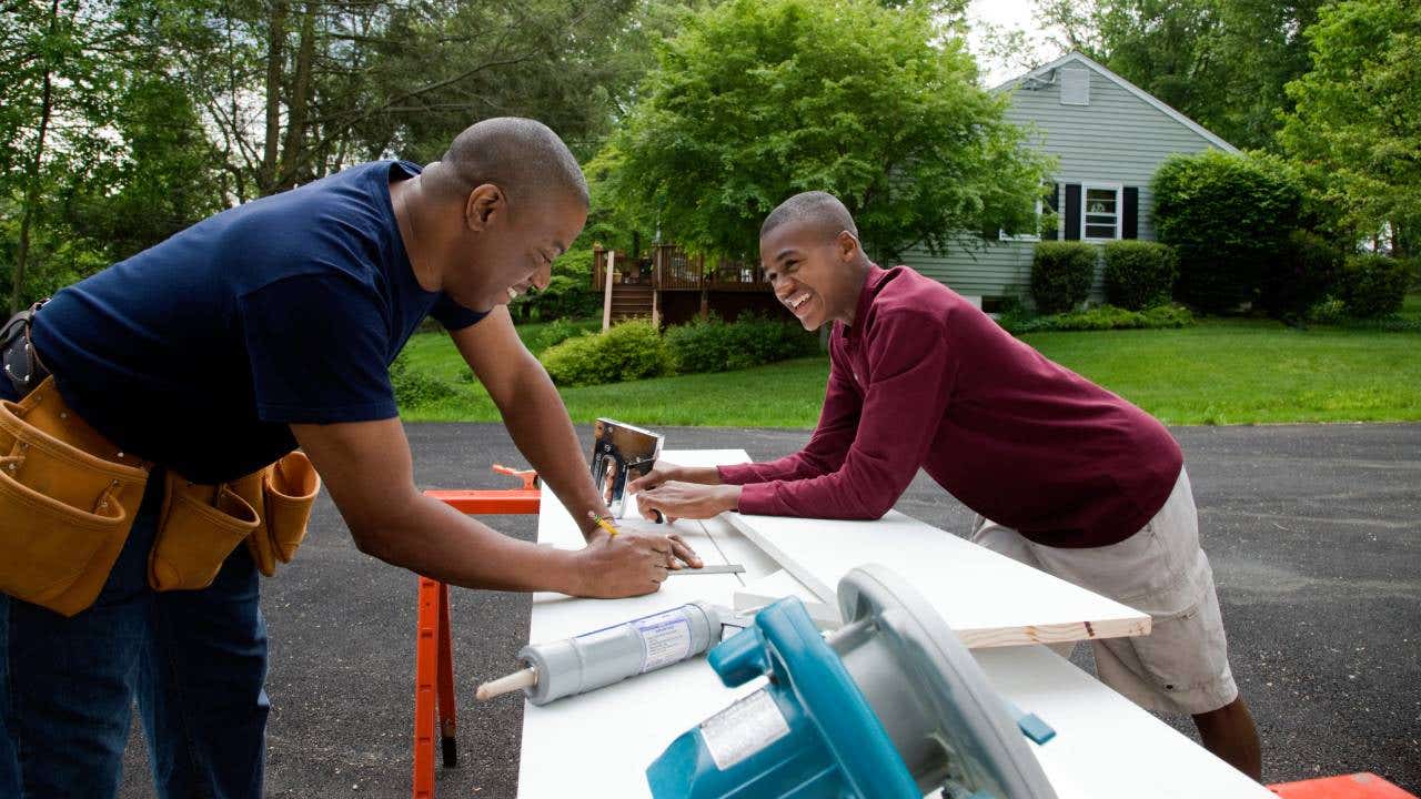 A father and son work on a project outside.