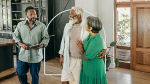 Smiling retired couple embracing each other while walking through home with their real estate agent