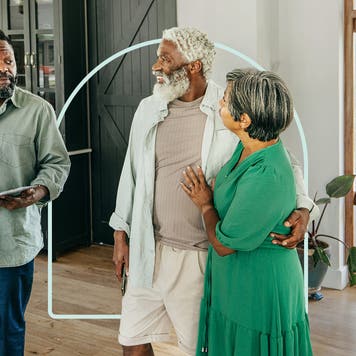 Smiling retired couple embracing each other while walking through home with their real estate agent