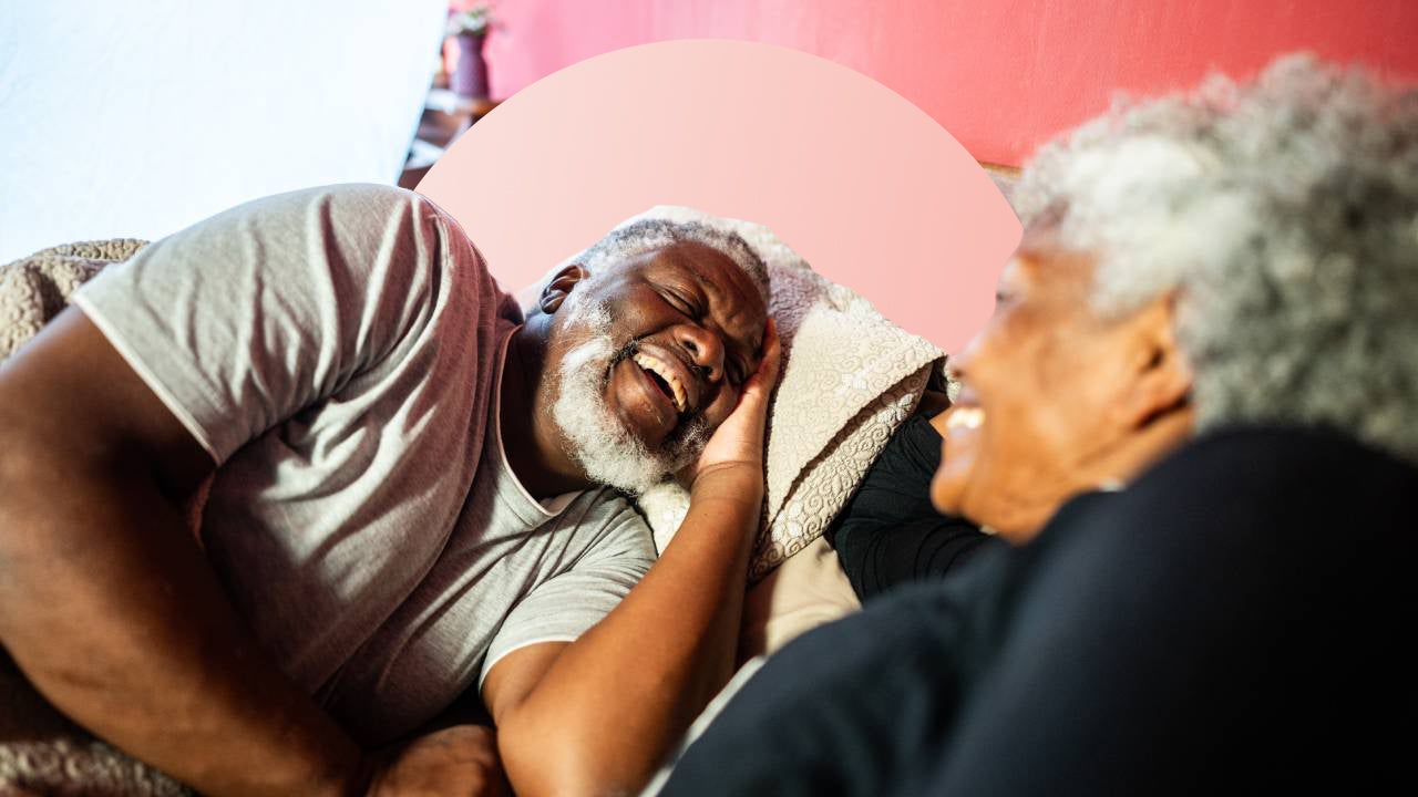 Two people laughing in bed.