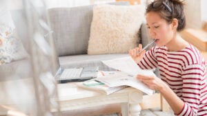 Mixed race woman paying bills on laptop - stock photo.