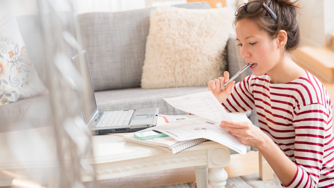 Mixed race woman paying bills on laptop - stock photo.