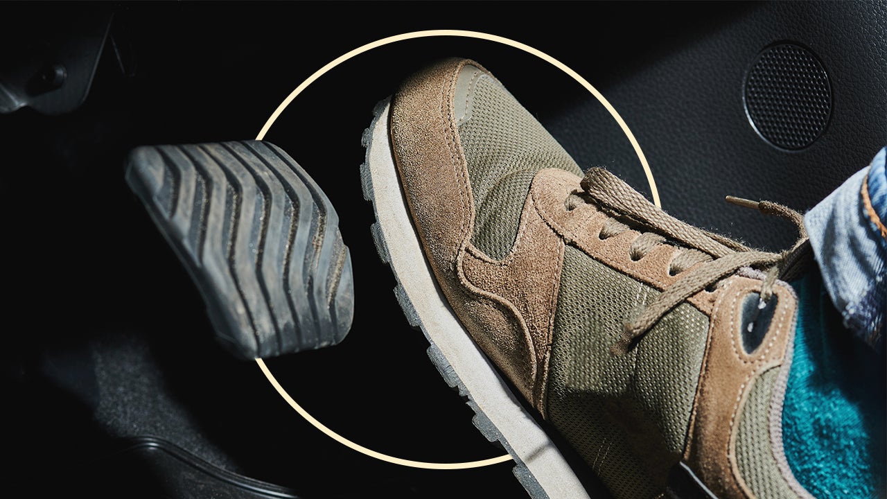 closeup of car driver's green and tan shoe hovering over brake pedal