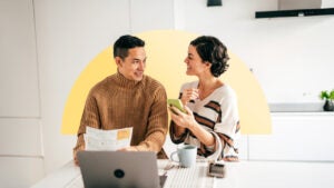 An Asian couple pays bills together in the kitchen.