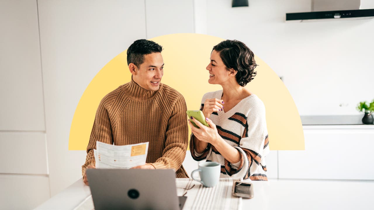 An Asian couple pays bills together in the kitchen.
