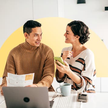 An Asian couple pays bills together in the kitchen.
