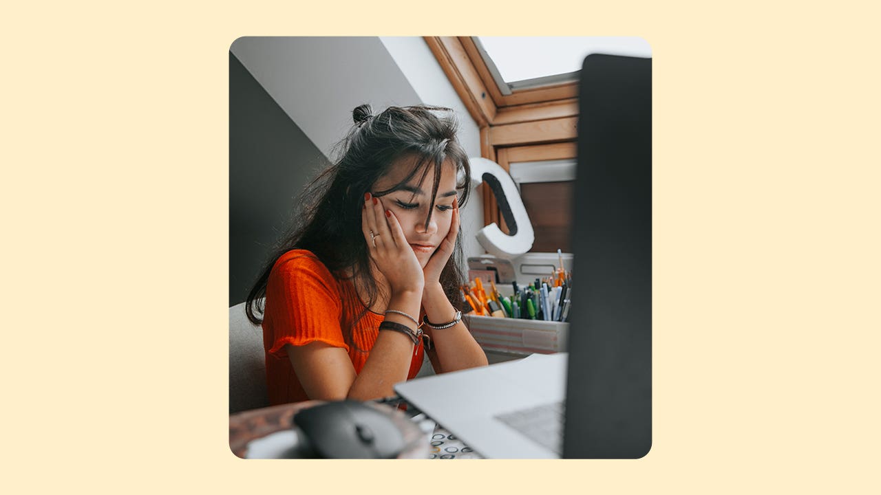 design image of a young woman with her hands to her cheeks looking down from her laptop