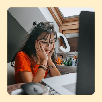 design image of a young woman with her hands to her cheeks looking down from her laptop