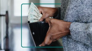 Image of a person's hands holding an open walled and pulling money from it.