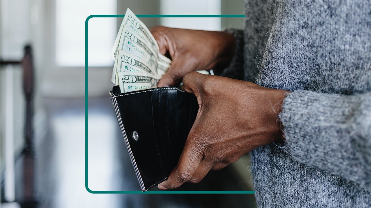 Image of a person's hands holding an open walled and pulling money from it.