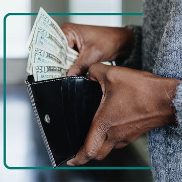 Image of a person's hands holding an open walled and pulling money from it.
