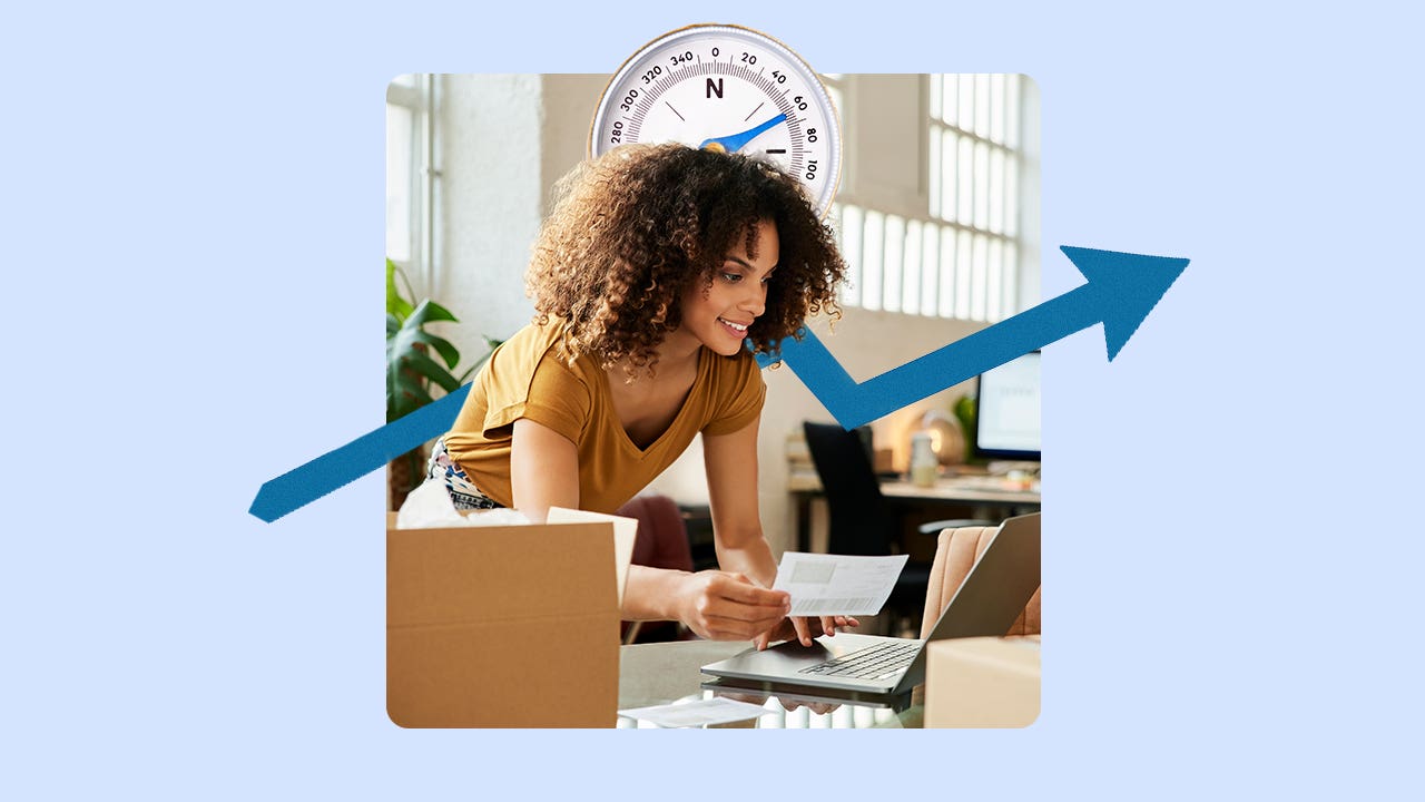 Image of a woman leaning over a desk working on a laptop. There is a large compass behind her head and a blue jagged arrow pointing from the lower left to upper right.