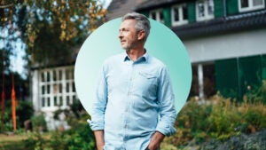 Middle-age man standing in front of his home looking at something in the distance