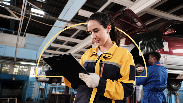 Female mechanic reading clipboard in garage