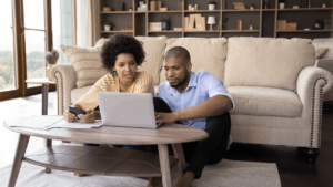Couple at home working on their finances on their laptop in the living room.