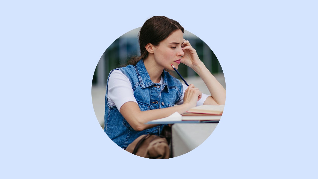 white brunette woman holding a black pencil and studying over a concrete surface