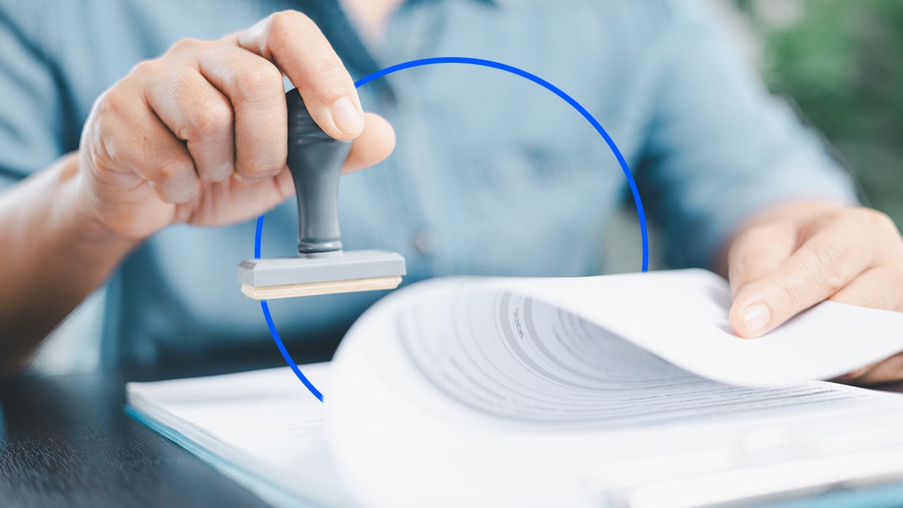 A hand applies a stamp to a document.