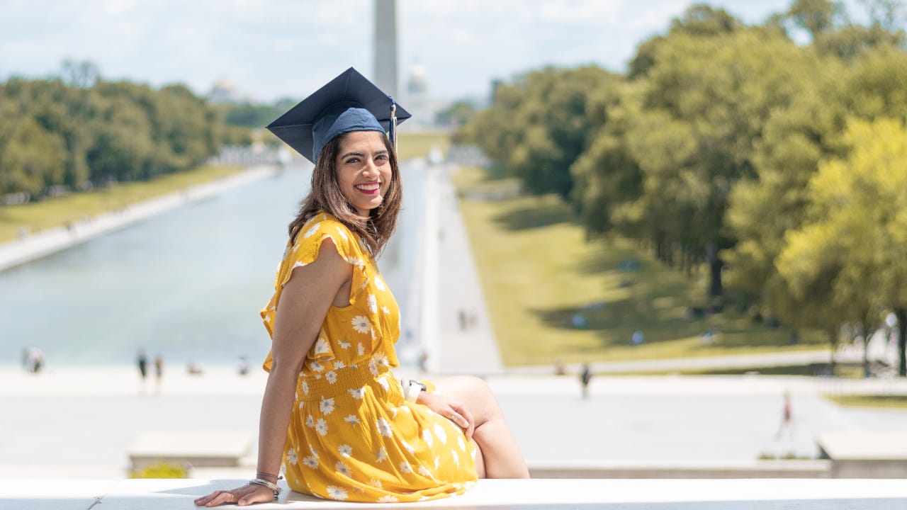 A graduating student sits on the steps overlooking the west mall in Washington DC