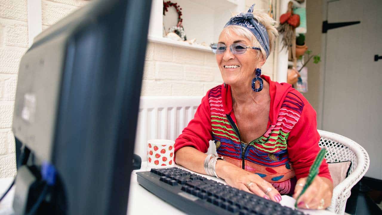 Happy senior woman sitting in front of a desk top computer.