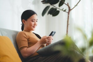 Young woman looks at phone while sitting on a sofa.