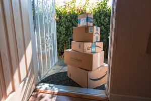 Image of Amazon packages stacked up on a sunny front porch.