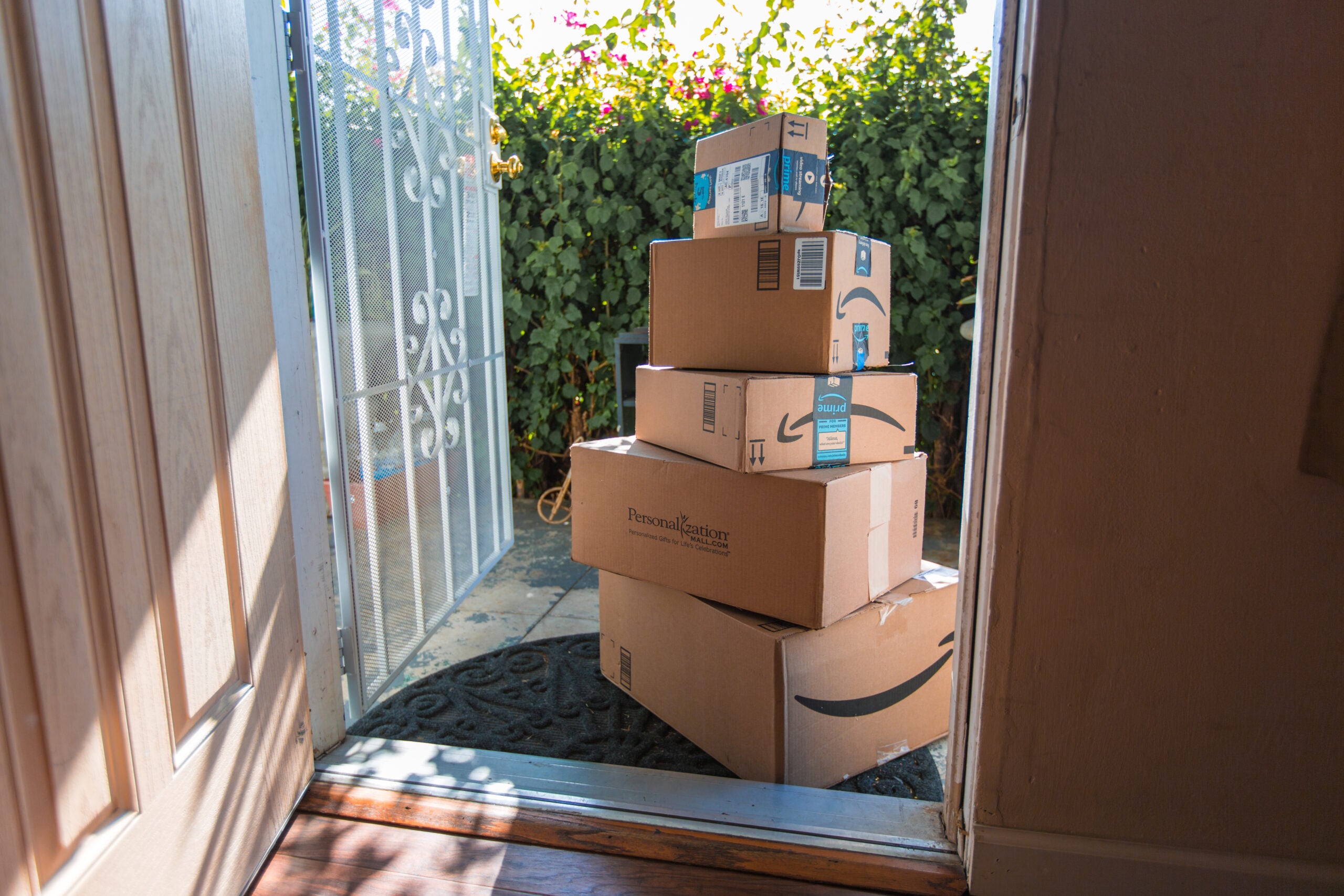 Image of Amazon packages stacked up on a sunny front porch.