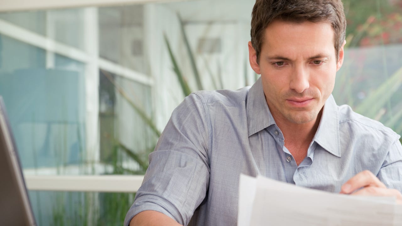 Young white man thoughtfully reviewing document.