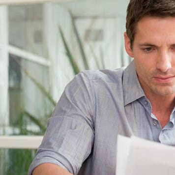 Young white man thoughtfully reviewing document.
