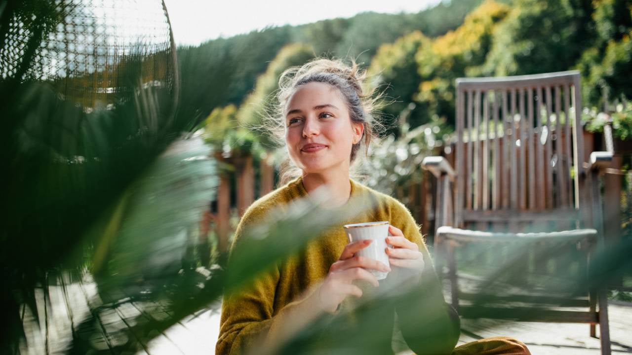 Woman with morning cup of coffee, sitting on patio and enjoying moment for herself.