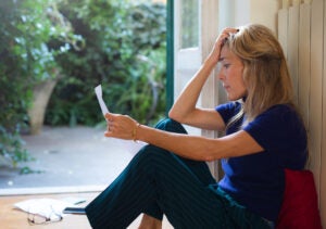 woman with frustrated reaction sitting on floor looking at letter