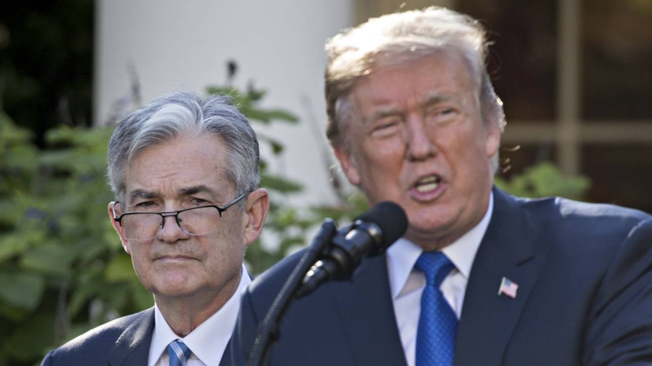 Federal Reserve Chair Jerome Powell standing behind President Donald Trump.