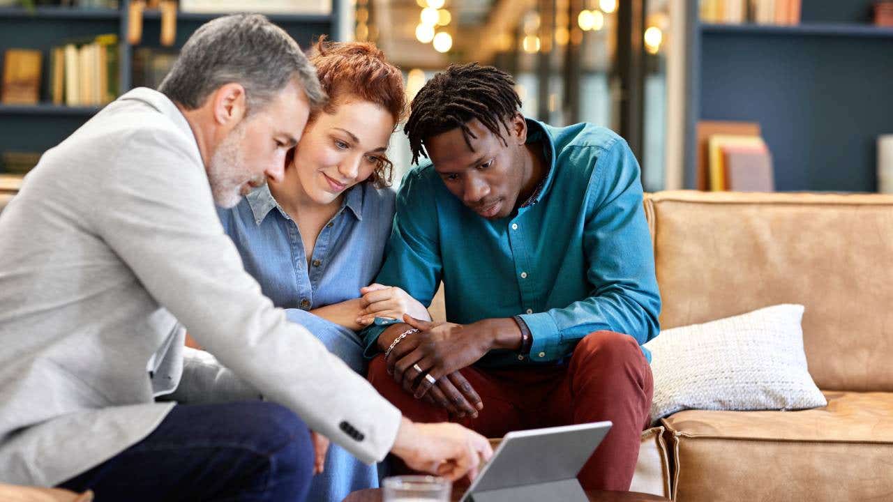 Financial advisor is planning investment with young couple during meeting.